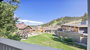 A hotel with a central courtyard, a mountain backdrop, and a large wooden wheel structure.