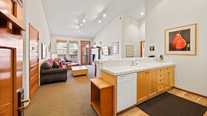 A compact kitchen with a dishwasher, wooden cabinets, and a small dining area.