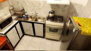 Une cuisine de taille réduite équipée d’une cuisinière à gaz, d’un évier et d’un four à micro-ondes.