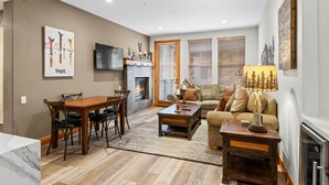 Ein Wohnzimmer mit Kamin, einer Essecke mit Holztisch und Stühlen sowie einem Sofa mit Lampe.