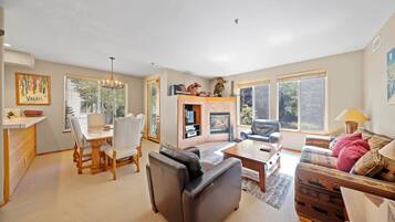 A spacious living room with a fireplace, a dining area with a table and chairs, and a cozy seating area with a sofa and armchairs.