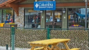 Uma mesa de piquenique de madeira em frente a uma loja de artigos esportivos com uma placa que diz 'Columbia Sportswear Company'.