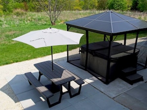 An outdoor patio with a table and chairs, a covered seating area, and a grill.
