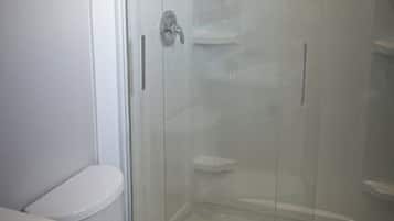 Ein Badezimmer mit einer Duschkabine, einer Toilette und einem Waschbecken.