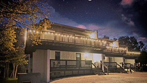 A two-story building with a balcony, a gravel driveway, and a starry night sky.