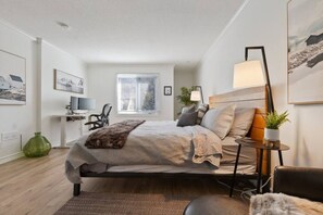 Une chambre moderne comprenant un lit, une table de chevet, une lampe et un bureau avec une chaise.