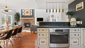 A modern kitchen with a central island, built-in oven, and a dining area with a wooden table and chairs. - Modern/Rustic 2 Story Condo/3 Min Walk to Village (The Blue Mountains)