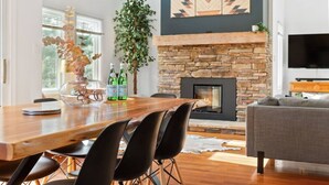 A modern living room with a stone fireplace, a dining area with a wooden table and black chairs, and a grey sofa. - Modern/Rustic 2 Story Condo/3 Min Walk to Village (The Blue Mountains)