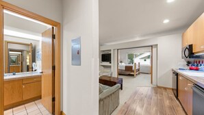 Hotelkamer met een houten deur, een badkamer met spiegel, een bed, een televisie en een kitchenette.
