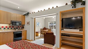 A compact kitchen with modern appliances, a dining area with a view, and a TV on a wooden shelf. - 253 | Studio w/ Mtn Views & A/C! Stay n Play! (Olympic Valley)