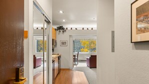 A modern kitchen with a dining area, wooden flooring, and a large window with autumn foliage view. - 253 | Studio w/ Mtn Views & A/C! Stay n Play! (Olympic Valley)
