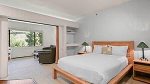 A modern bedroom with a large bed, two bedside tables with lamps, a chair, and a desk.