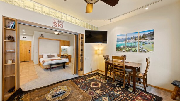 A cozy room with a bed, a dining table, and a TV mounted on the wall. - 243 | Premium Studio - Mtn Views + Pool Escape (Olympic Valley)