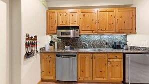 A kitchen with wooden cabinets, a stainless steel microwave, a sink, and a dishwasher. - 243 | Premium Studio - Mtn Views + Pool Escape (Olympic Valley)