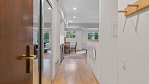 A hallway leading to a dining area with a wooden table and chairs, a radiator, and a window with a view of trees. - 232 | Updated Studio w/AC! - Pool View + Parking (Olympic Valley)