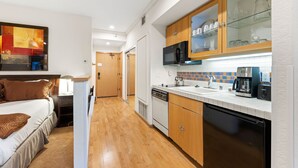 A compact kitchen with wooden cabinets, a microwave, a coffee maker, and a dishwasher. - 232 | Updated Studio w/AC! - Pool View + Parking (Olympic Valley)