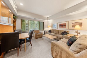 Uma sala de estar moderna com sofá, cadeiras, uma mesa de jantar e um abajur.