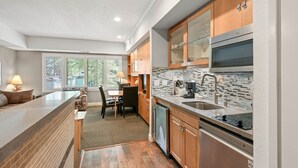 A modern kitchen with wooden cabinets, a stainless steel range, and a large window providing natural light.