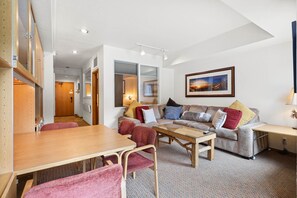 A cozy living room with a wooden table, red chairs, a sofa with multiple cushions, and a framed picture on the wall. - 223 | Relaxing Studio - Spas, Sauna & Pool Too (Olympic Valley)
