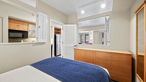Une chambre à coucher comprenant un lit, une commode, un miroir et une porte donnant sur une salle de bain.