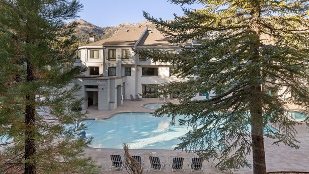 A two-story house with a swimming pool, surrounded by trees.