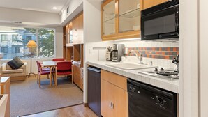 A modern kitchen with wooden cabinets, a black microwave, and a tiled backsplash.