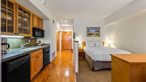 Camera d'albergo compatta con angolo cottura, un letto e un piccolo comodino.