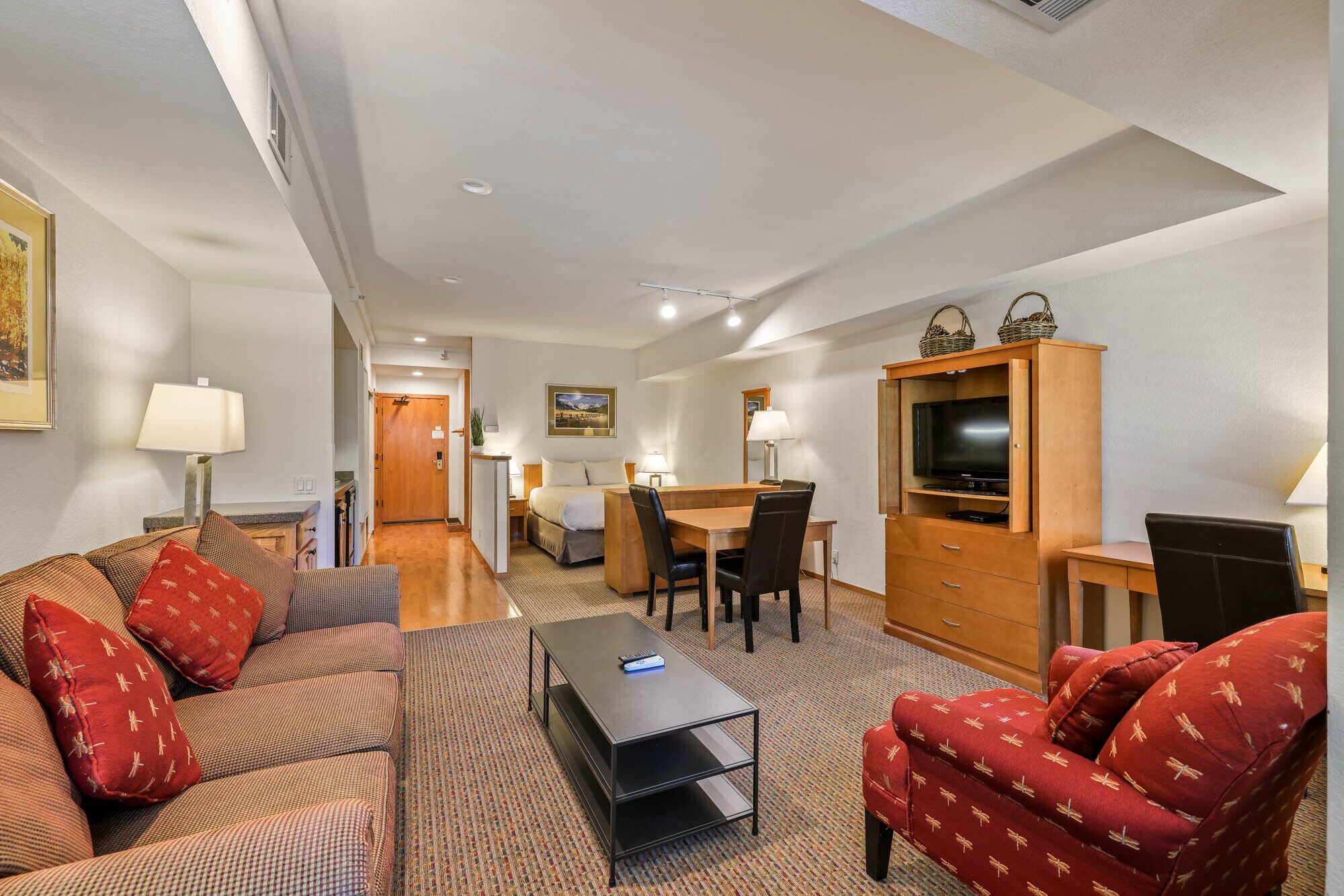 Une chambre d’hôtel comprenant un canapé, une table basse, un meuble pour la télévision et un coin repas avec une table et des chaises.