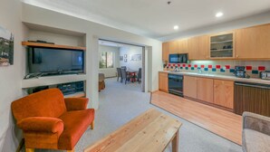 A compact living space with a TV, seating area, and kitchenette.