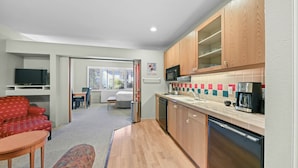A compact kitchen with wooden cabinets, a microwave, a coffee maker, and a dishwasher.