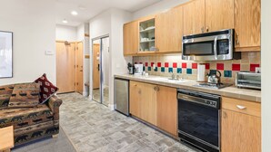 Una cocina moderna con armarios de madera, microondas, lavavajillas y salpicadero de azulejos.
