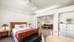 Un dormitorio con cama de madera, un escritorio, una silla, un aparador y una mesa de comedor.
