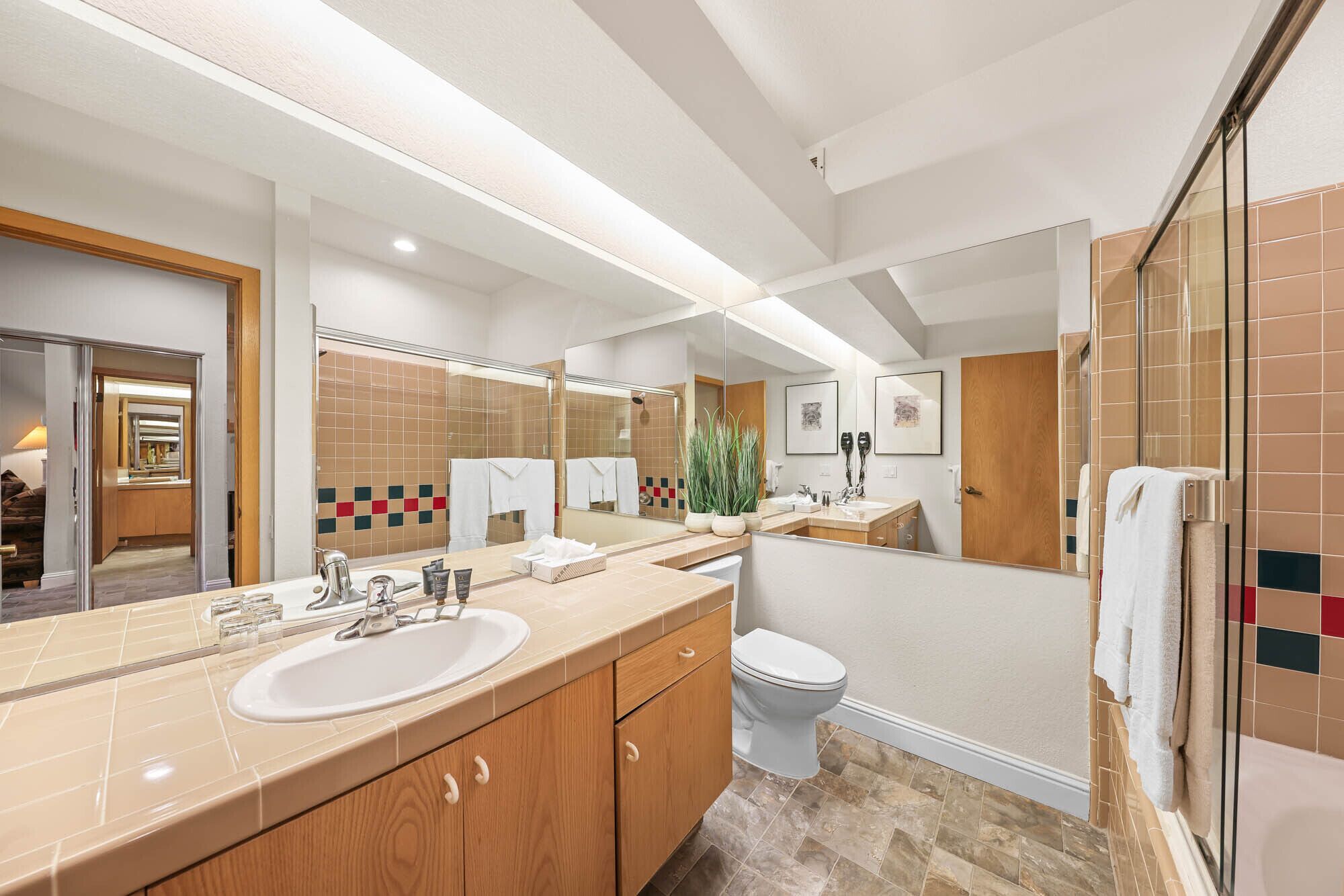 Une salle de bain moderne avec un grand miroir, un lavabo, des toilettes et un espace douche.