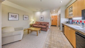 A compact living area with a sofa, a coffee table, and a couch. There is a kitchenette with a sink, stove, and cabinets. - 148 | Affordable Studio - Mtn Escape w/ Pool & Spa (Olympic Valley)