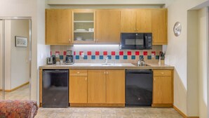 A compact kitchen with wooden cabinets, a microwave, a dishwasher, and a tiled backsplash. - 148 | Affordable Studio - Mtn Escape w/ Pool & Spa (Olympic Valley)