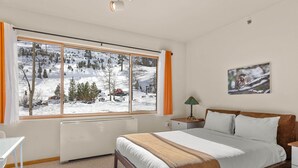 A bedroom with a large window, a bed, a bedside table, and a lamp. - 147 | Studio Escape - Tubs, Trails & Tranquility (Olympic Valley)