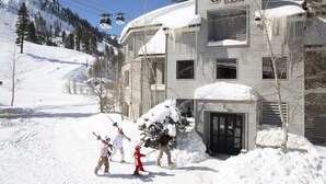 Un bâtiment avec un télésiège en arrière-plan, entouré de neige.