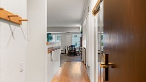 A hallway with a wooden door, white walls, and a tiled backsplash.