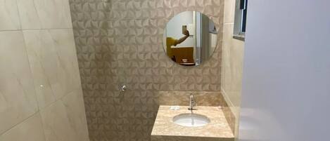 A bathroom with a patterned wall, a round mirror, and a sink with a faucet.