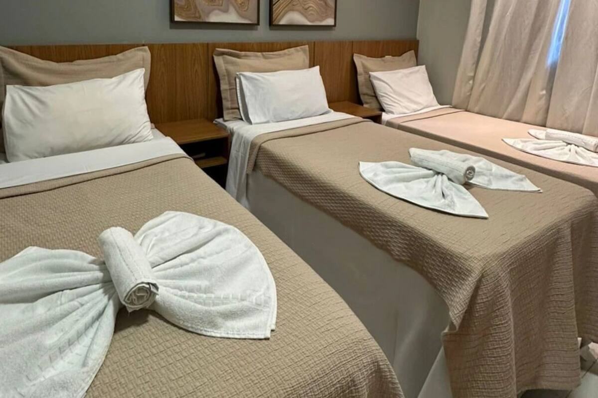 A hotel room with two beds, each with a towel and pillow.