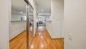 A hallway with wooden flooring, white walls, and a glass door leading to a dining area with a table and chairs. - 104 | Peaceful Studio - Hot Tubs + Nature Walks (Olympic Valley)