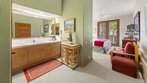 A bathroom with a large mirror, wooden cabinets, a sink, and a red rug.