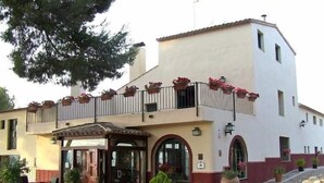 A two-story building with a balcony adorned with potted plants. - Hôtel rural castillo de biar (Biar)