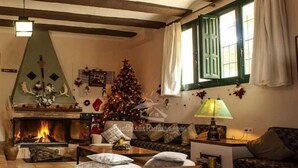 A cozy living room with a fireplace, a Christmas tree, and a sofa. - Hôtel rural castillo de biar (Biar)