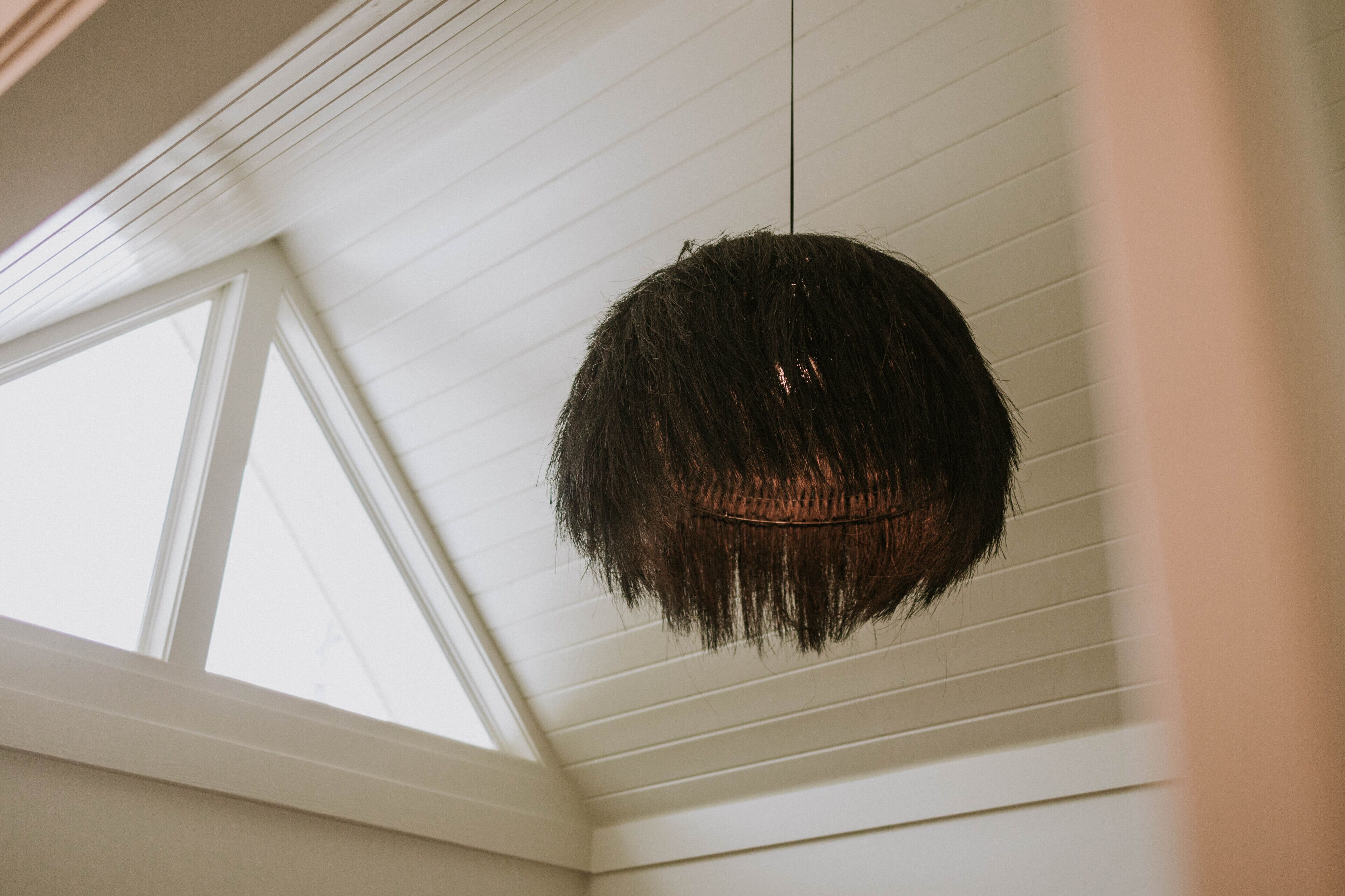 A ceiling with a hanging light fixture and a skylight.
