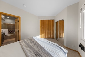 Ein Schlafzimmer mit Bett, ein Badezimmer mit Dusche und ein Kleiderschrank mit Schiebetüren.