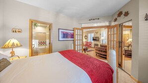 Ein Schlafzimmer mit einem großen Bett, ein Badezimmer mit Dusche sowie ein Essbereich mit Tisch und Stühlen.