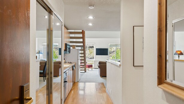 Een modern interieur met een keuken, een eethoek en een trap naar een hoger gelegen verdieping.