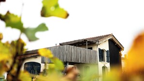 Un bâtiment doté d’un toit en pente, d’un balcon en bois et d’une grande fenêtre en arc de cercle.