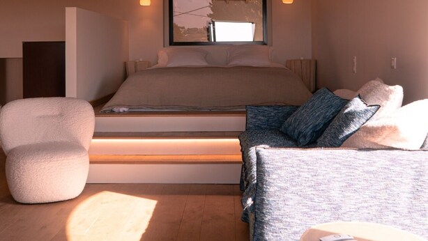 Une chambre à coucher avec un lit, un canapé, une chaise et une petite table.